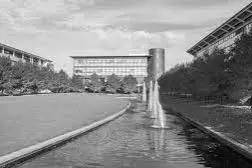 Fountains in a canal with grass, trees, and surrounding buildings